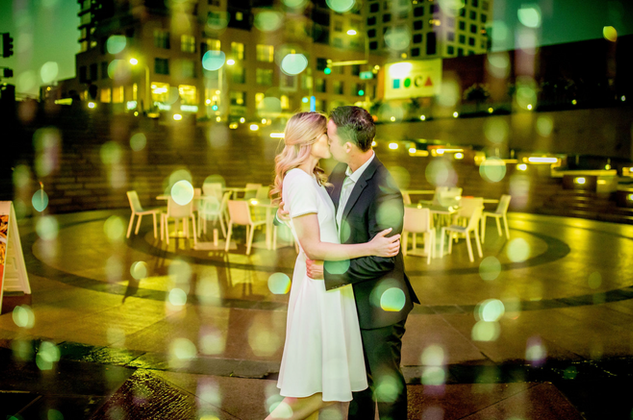 Romantic engagement photo of a couple kissing in city lights