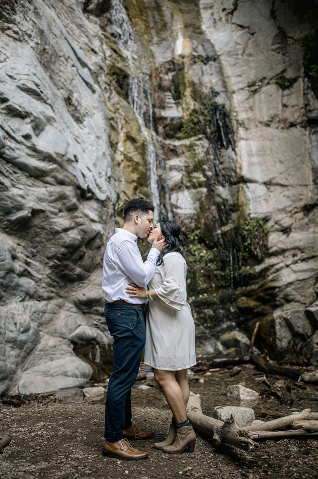 Couple kissing in front of a waterfall