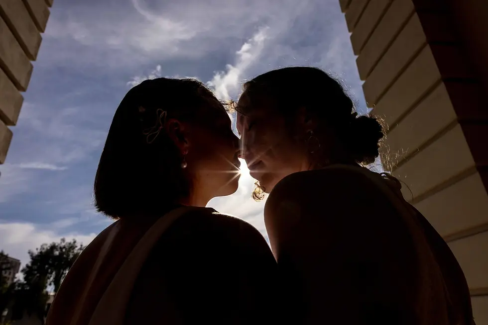 Silhouette of a couple about to kiss against a cloudy sky.