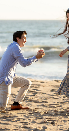 Man proposes to woman on a sandy beach. Engagement photo.