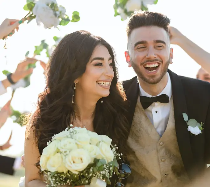 couple running in balboa park for fun romantic photos on their wedding day as the wedding party makes a bridge for them to go under fun smiles and laughter