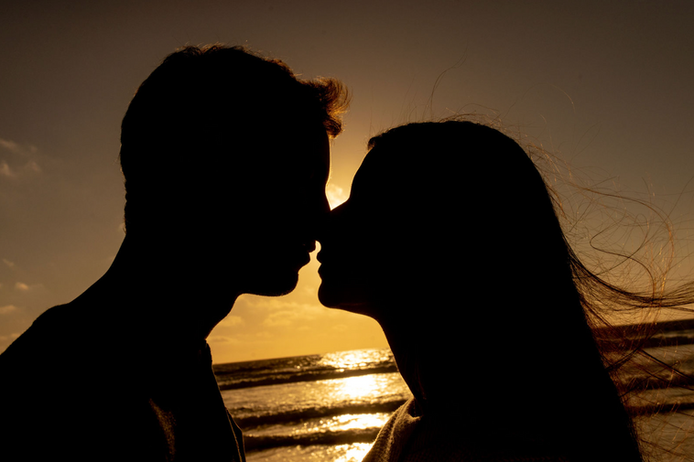 Romantic engagement photo of couple silhouetted at sunset