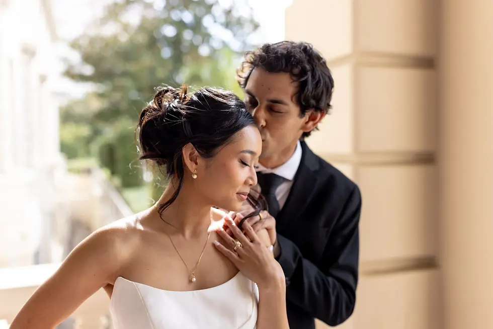 groom kisses his bride on the temple