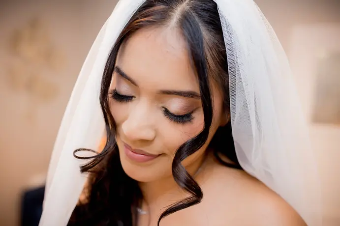 a bride looks down at her bridemaids as they put on her shoes
