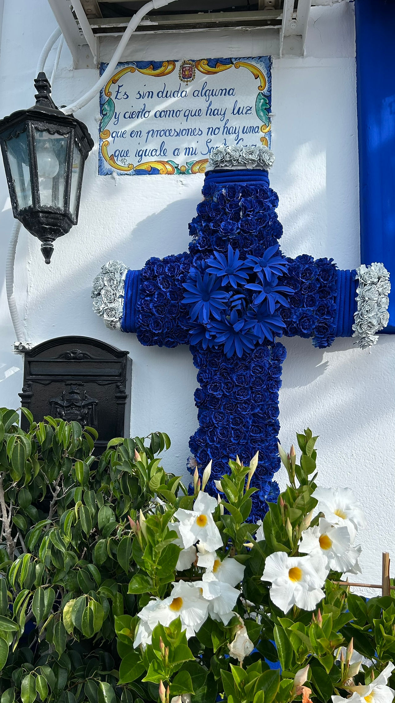 Ein blaues Kreuz gebastelt aus Blumen.