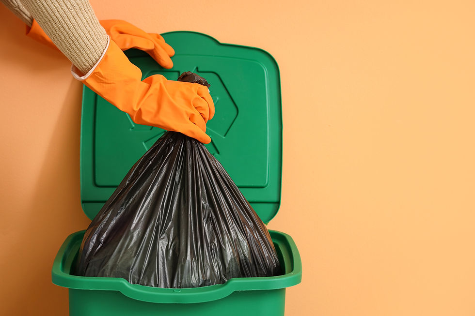 Woman taking garbage bag from trash bin near orange wall, closeup.jpg