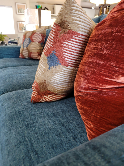 Teal couch with patterned and velvet pillows