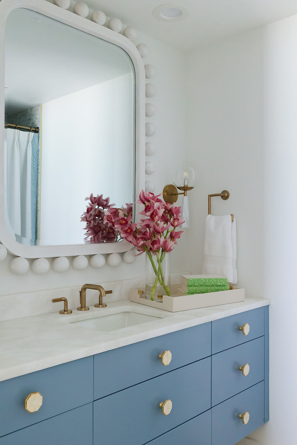 bathroom vanity with custom blue cabinets, white mirror, and gold accents