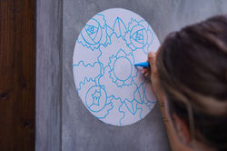 Female artist painting a floral design on a wall for Villa Alba