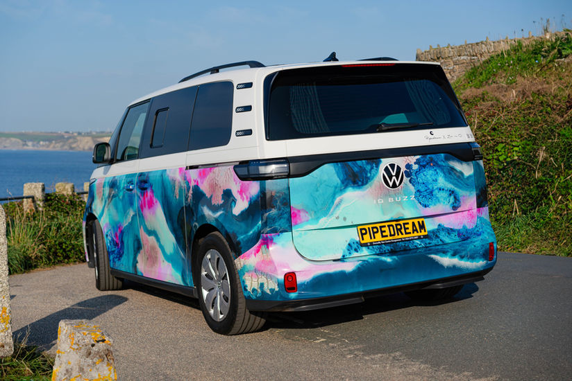 Volkswagen ID Buzz camper van with colorful art wrapping by the ocean