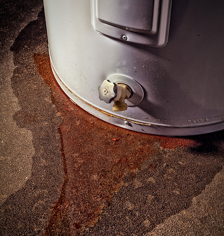 Water leaking from a residential electric water heater sitting on a concrete floor with si