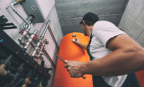The technician checking the heating system in the boiler room with tablet in hand.jpg