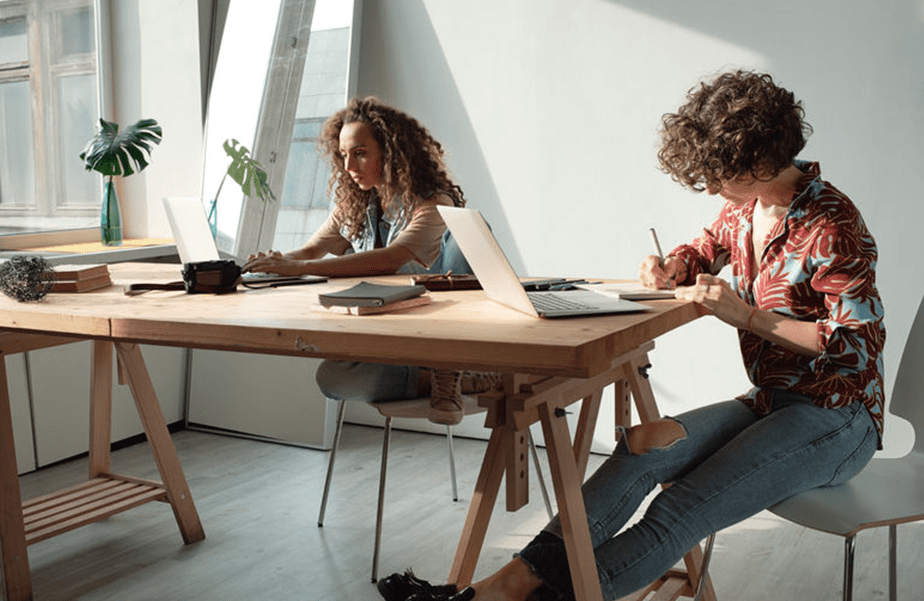 Zwei Mitarbeiterinnen am Schreibtisch mit Computer in sonnigem Büro