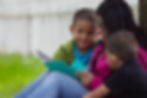Mother reading to children at a park while using a new wireless device for new company