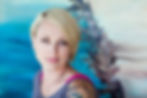 Professional headshot of woman with short blonde hair against a colorful background