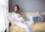 Pregnant woman seated by a window during a lifestyle maternity photography session