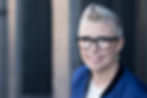 Professional business headshot of woman wearing glasses and a dark jacket