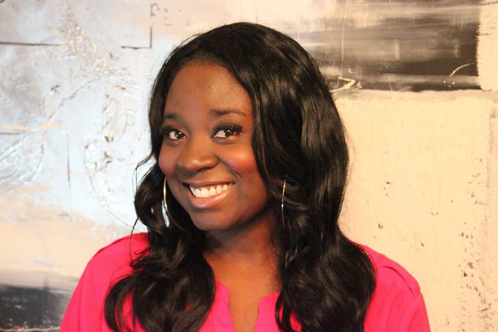 Mwati Mwila, smiling young black woman with long hair and pink shirt