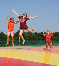 Smiling kids jumping on a large jumping pillow