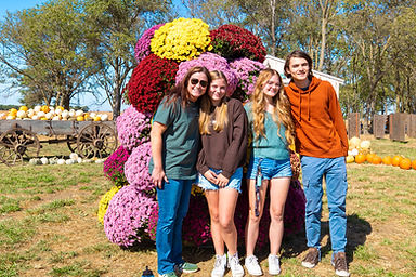 Four friends smiling in front of a giant flower display.