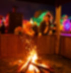 People roasting food over a bonfire at a night market.
