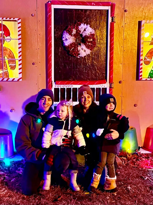 Family posing in front of a gingerbread house display
