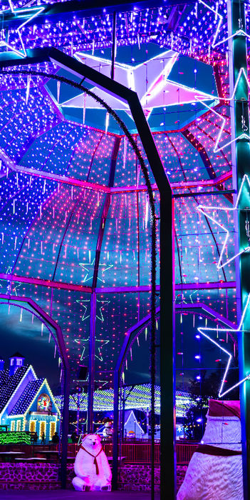 Vibrant blue and pink holiday light display with stars.