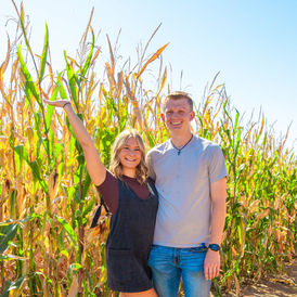 A couple posing in front of a cornfield at a Fall Festival.