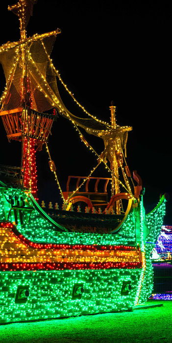 Large pirate ship sculpture covered in green and gold lights