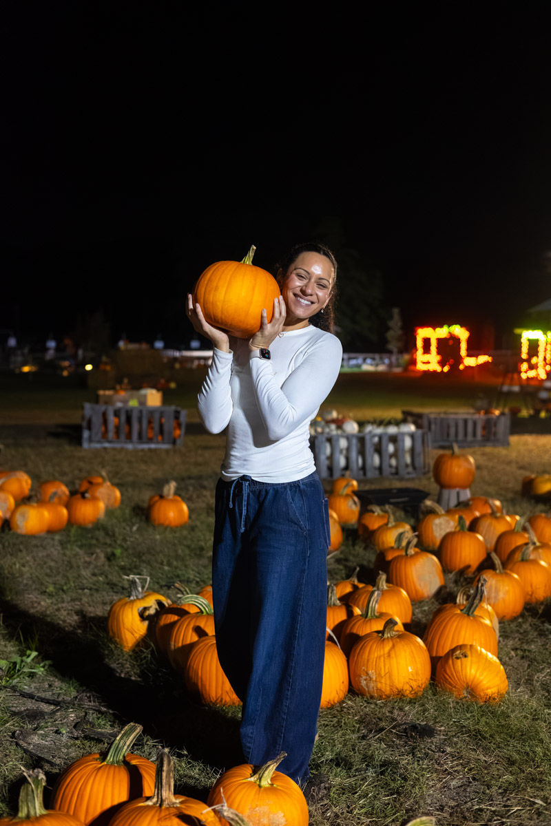 Woman holding a pumpkin in a patch at night