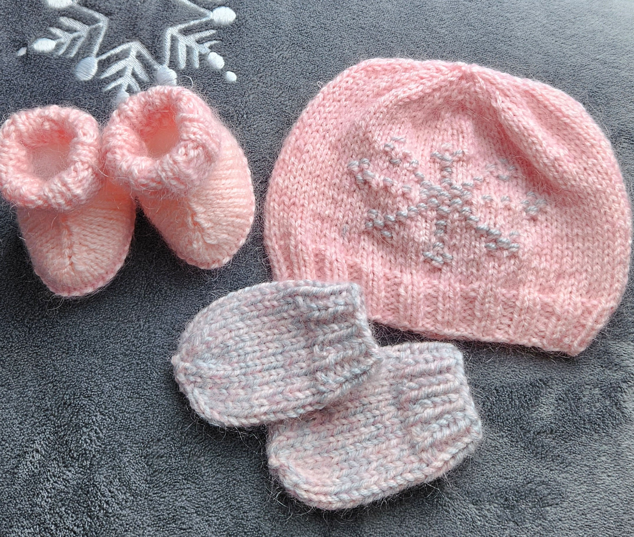 Baby girl gift set of pink hat with snowflake design, matching booties, and baby mittens without thumb.