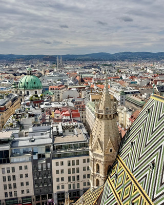Ausblick vom Südturm des Stephansdoms in Wien über die Innenstadt mit markantem Dachmuster, Stadtpanorama und grüner Kuppel der Peterskirche