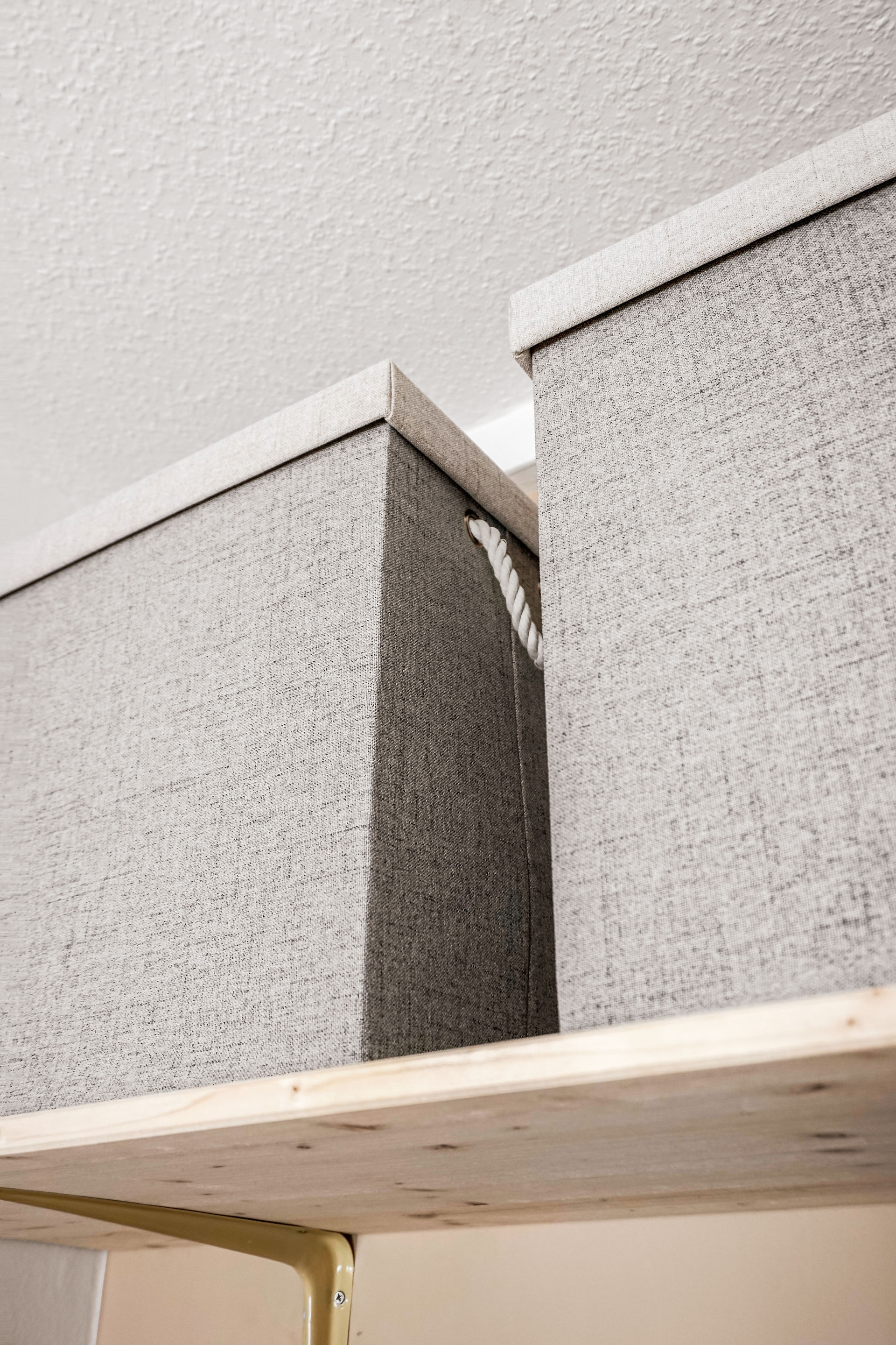 Graue, texturierte Boxen auf Holzregal