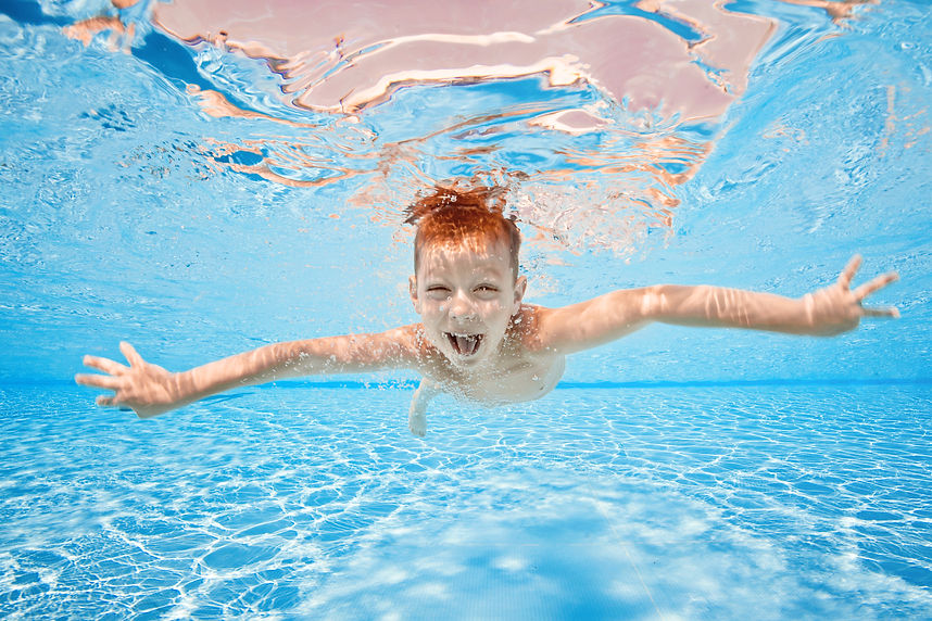 Happy young boy swim and dive underwater, kid breast stroke with fun in pool. Active healt