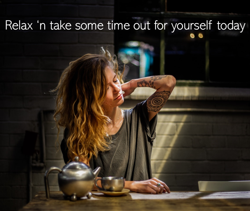 Woman with tattoos sits at a table, resting her head, beside a teapot in sunlight. Text: Relax 'n take some time out for yourself today.