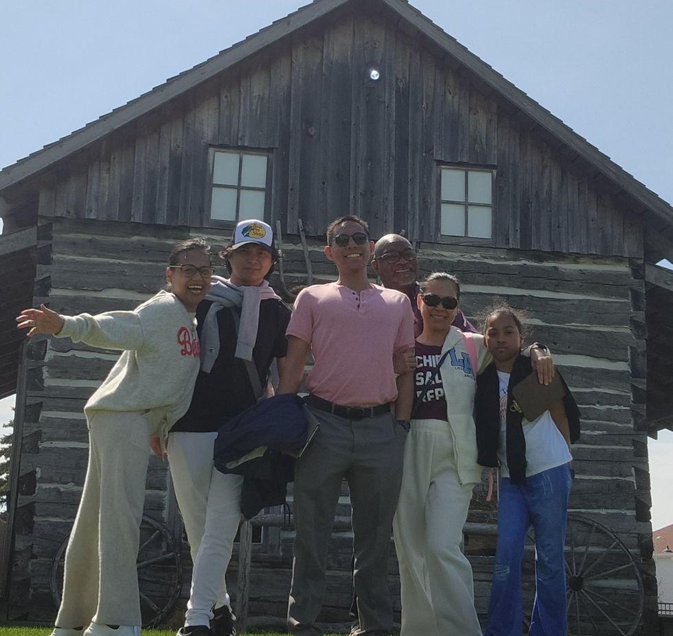Family picture in front of a rustic wooden cabin, enjoying a sunny day out together.