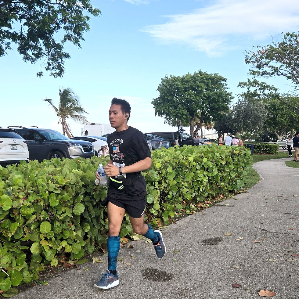 A determined runner (my son) maintains his pace, fueled by motivation, as he navigates a scenic path lined with greenery and a backdrop of parked cars and palm trees.