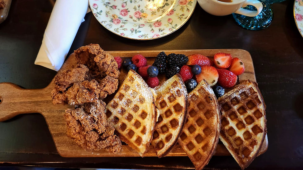 Crispy fried chicken paired with golden waffles and a medley of fresh berries served on a rustic wooden board for a delicious brunch treat.