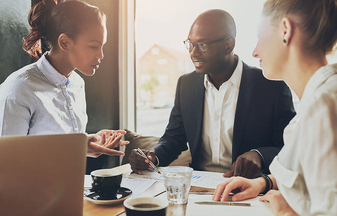 Photo of three Melli employees sitting at a table, having a discussion