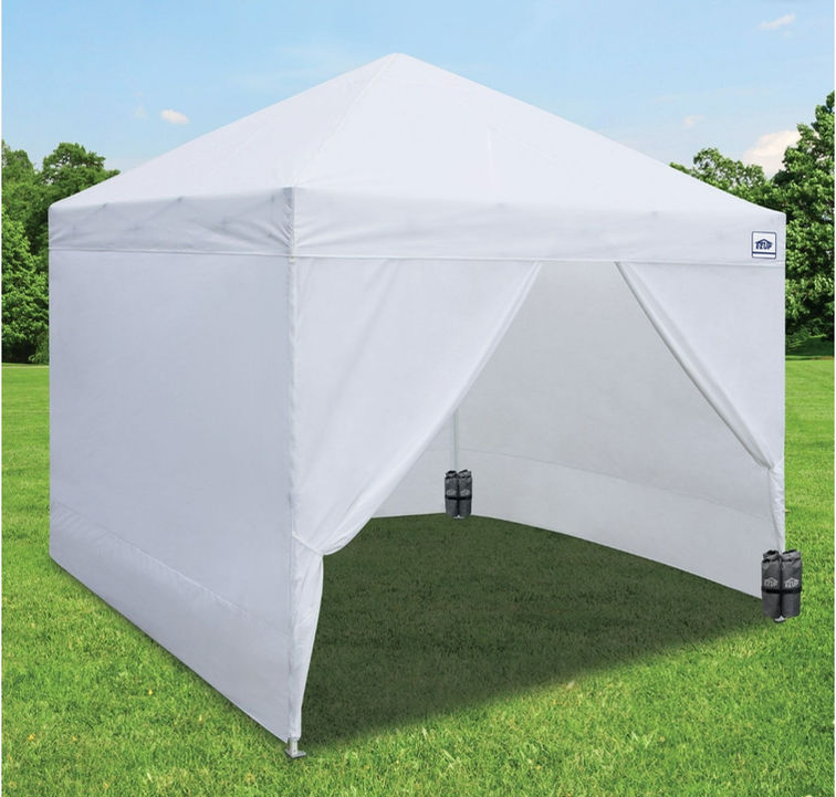 White pop-up canopy tent set on a green grassy field.