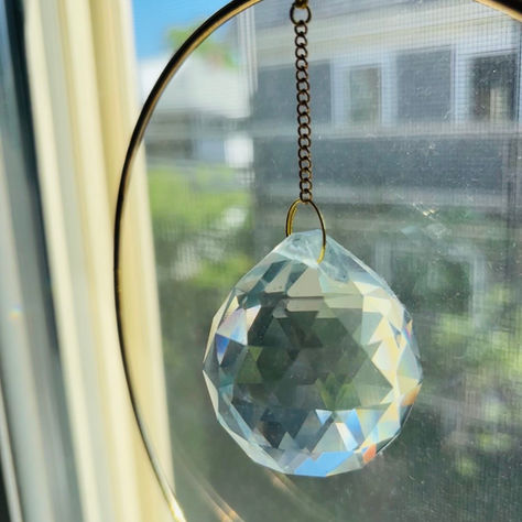    A glass sun-catcher in a window, scattering small fragments of light across a room, a gentle image of courting joy for highly sensitive people recovering from sensory overwhelm