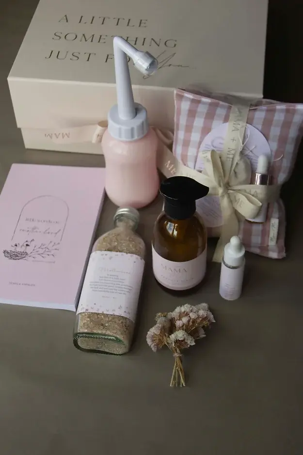 contents in giftbox including peri bottle, bath soak, padsicle serum, motherhood book, wheat bag, oil