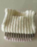 Folded trio of hand-knitted merino baby vests/singlets
