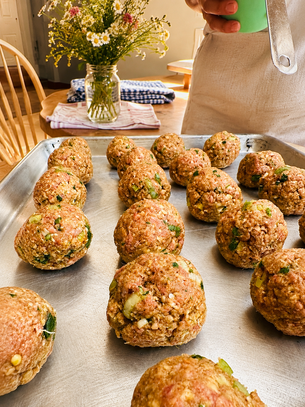 Rolled up meatballs, set out on a baking tray.