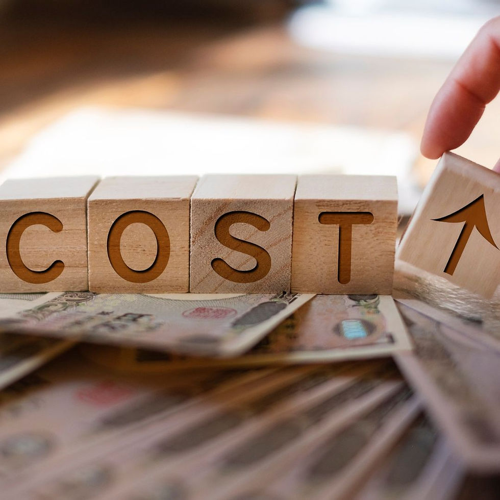 Wooden blocks spelling "COST" with an arrow block added, symbolizing rising costs. Background shows scattered money and a warm tone.