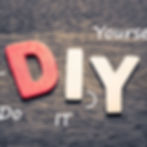 Wooden letters spell "DIY" on a dark textured background. Red "D" and beige "IY." White text reads "Do It Yourself" with arrows.