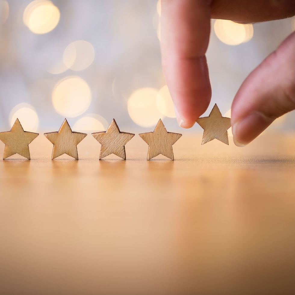 Five wooden stars on a table with fingers arranging them. Soft bokeh lights in the blurred background create a warm, focused mood.