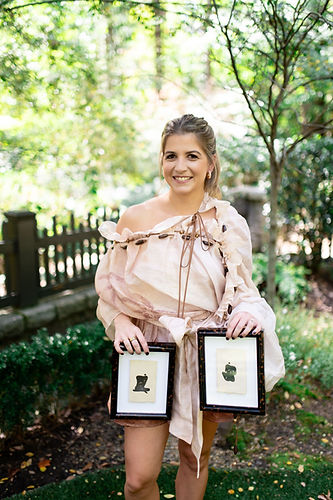 Hayley Price White holding two of her figurative paintings.