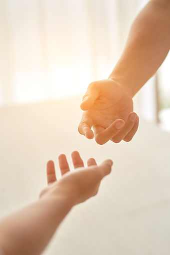 hands-couple-extended-each-other-against-sunlit-room.jpg