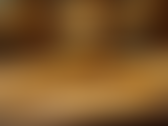 Stacks of gold coins and chains on a textured surface with a blurred golden backdrop, conveying opulence and wealth.